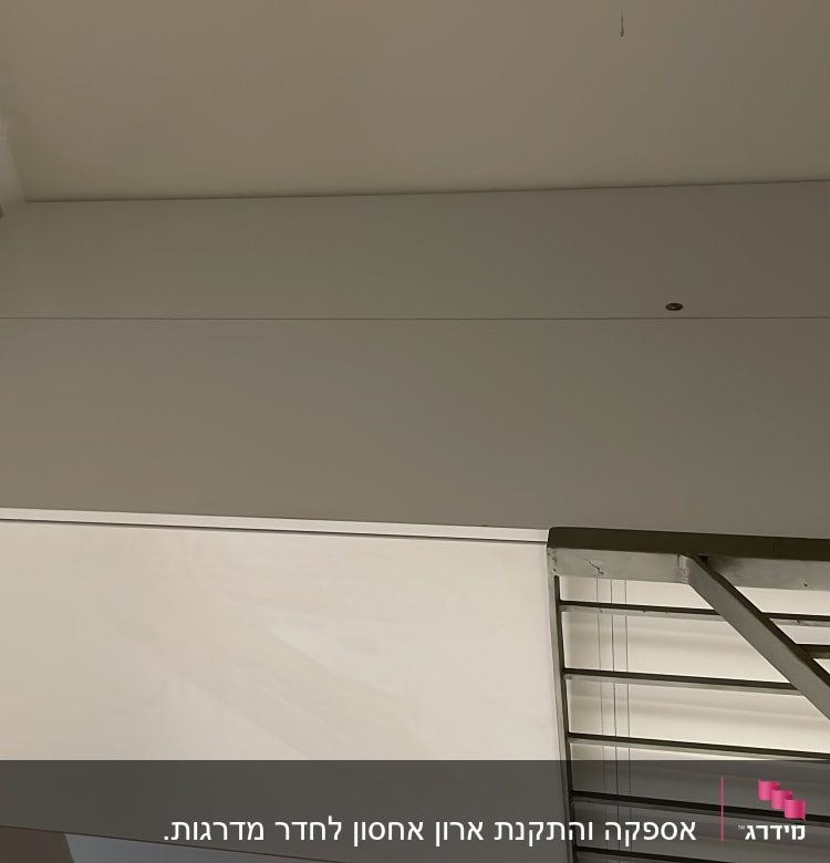 קיר לבן עם דלתות ארון ומעקה מתכת